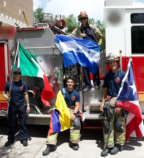 AAHFF members on a fire engine holding the flags of Mexico, Honduras, Colombia, and Puerto Rico